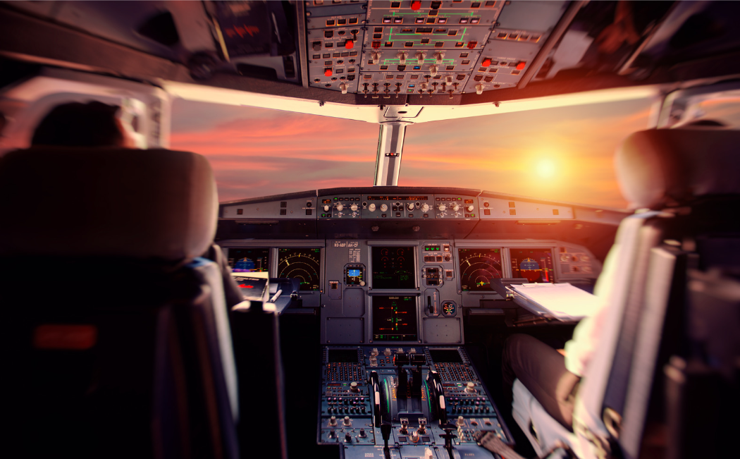 Pilotos subidos en la cabina de un avión y observando la puesta de sol